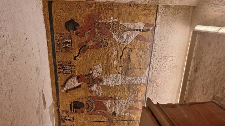 Colourful wall paintings depicting Egyptian deities inside a Valley of the Kings tomb corridor.