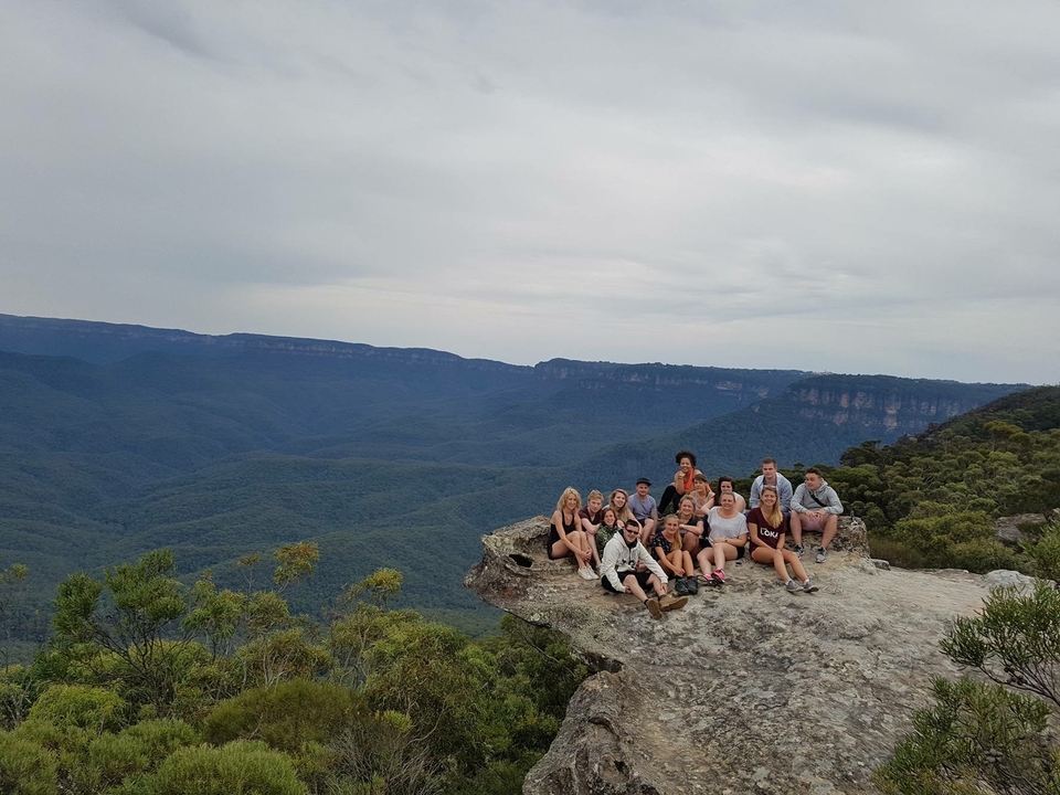 Group sitting at a rock ledge overlooking vast valleys.