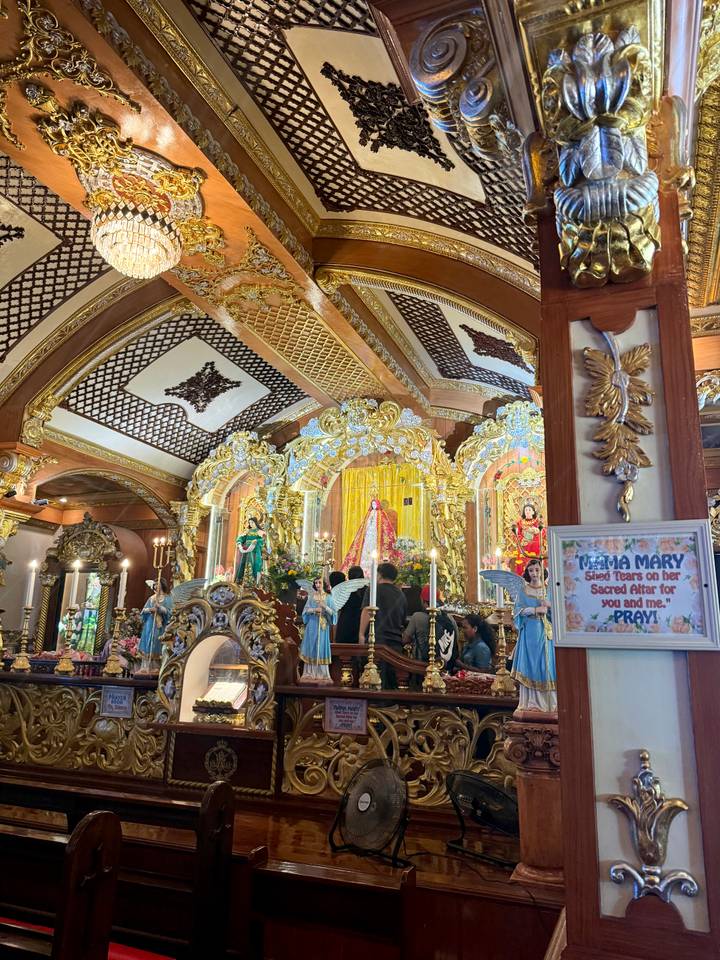 Lavish, gold-trimmed Catholic altar filled with statues, candles and worshippers inside an ornate church.