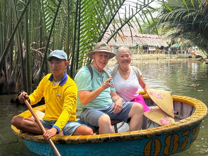 Tourists sit in a round basket boat paddling through lush nipa palm waterways.