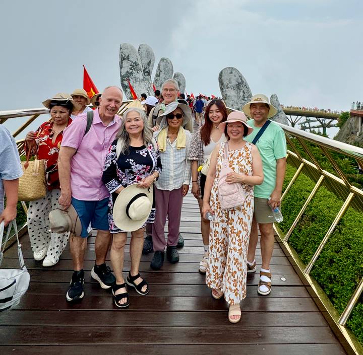 Group photo of travellers standing on Vietnam’s Golden Bridge with forested hills beyond.