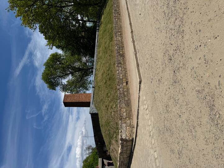 Low grassy mound with a solitary brick chimney against a blue sky with wispy clouds.