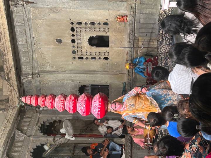 Traditional Rajasthani dancer balances a tall stack of pots during an indoor cultural performance.