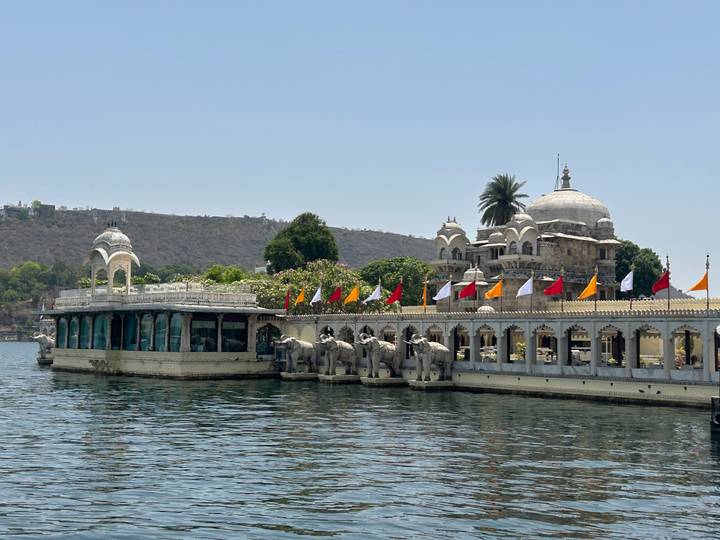 Lakeside palace complex with elephant statues and colorful flags on Lake Pichola.