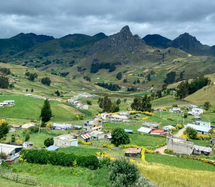 High-altitude Andean village with patchwork fields and green valleys beneath rugged mountains.