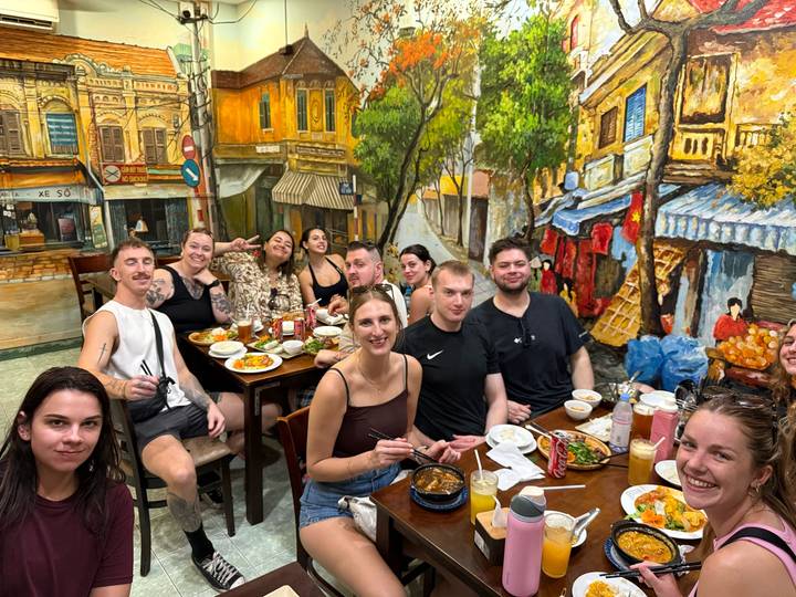 Large group enjoys Vietnamese dishes together in a colourful local restaurant.