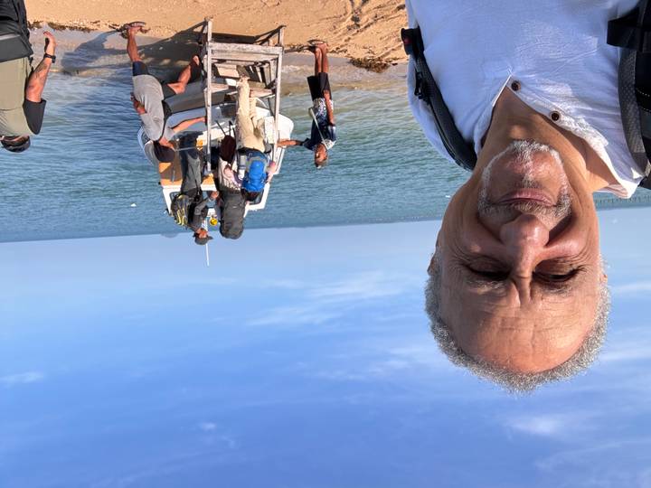 Travellers boarding a speedboat from shore on a sunny tropical morning, selfie in foreground.