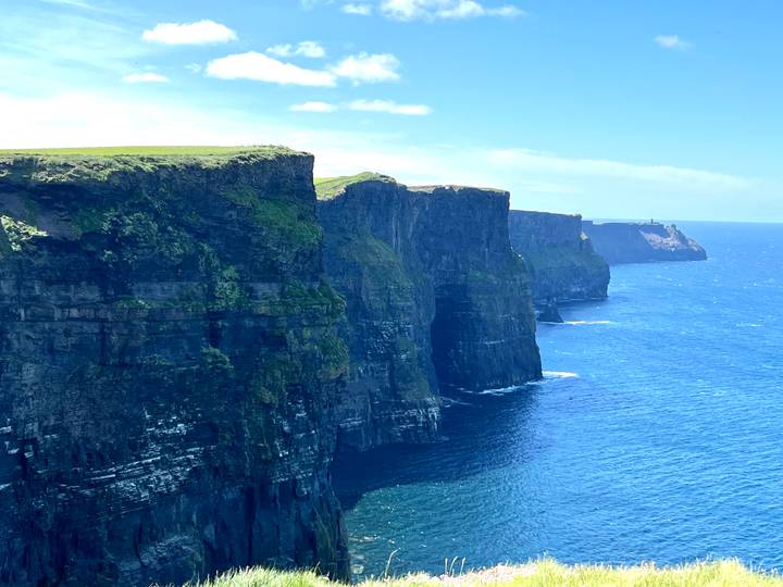 Iconic vertical cliffs plunge into the Atlantic at the Cliffs of Moher under bright sunshine