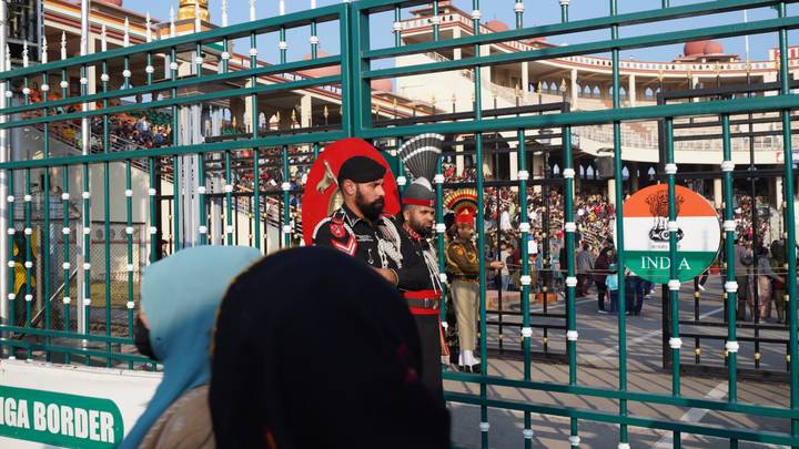 Pakistani and Indian soldiers stand at iron gates during the border ceremony as spectators look on.