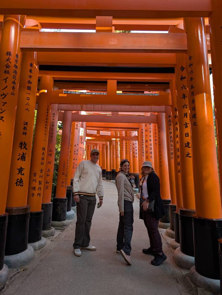 Visitors standing among the vivid orange torii gates at Fushimi Inari Shrine