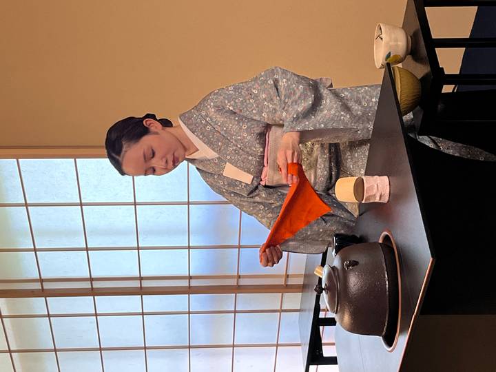 Tea ceremony host in traditional kimono preparing utensils indoors