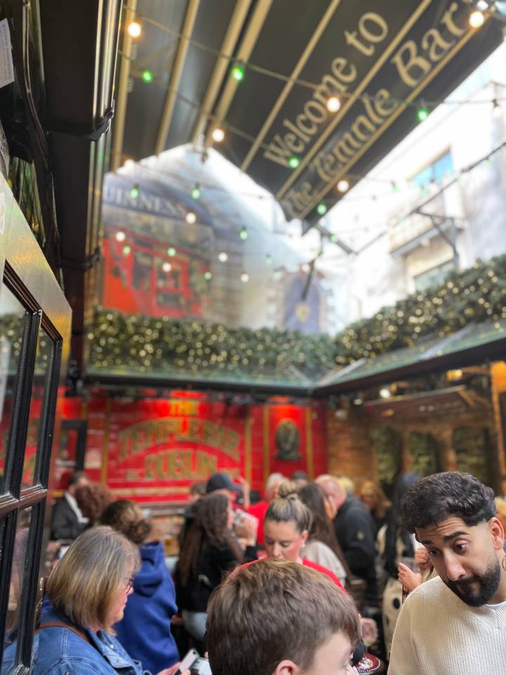 Soft-focus indoor shot of a festive pub courtyard decorated with lights and greenery.