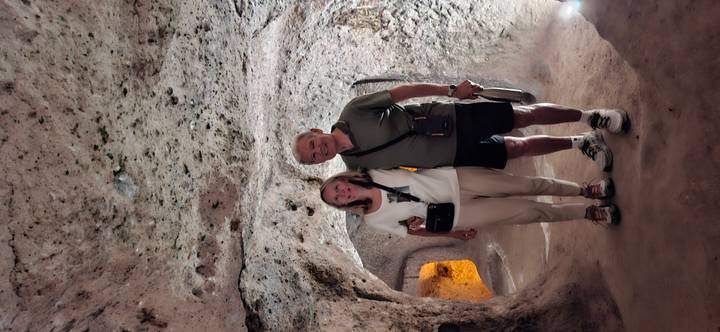 Older couple posing inside a dimly lit volcanic rock chamber of Cappadocia underground city
