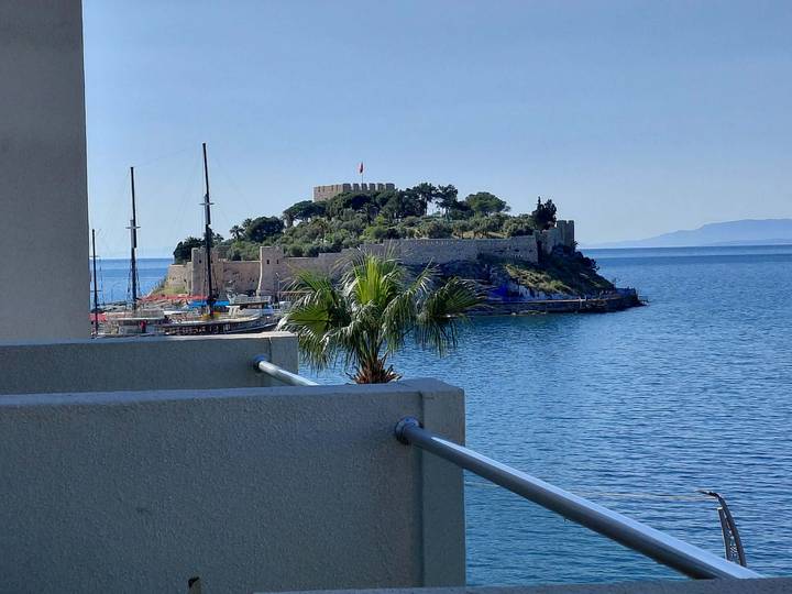 Island fort and sailing boats seen across blue Aegean waters from Kusadasi