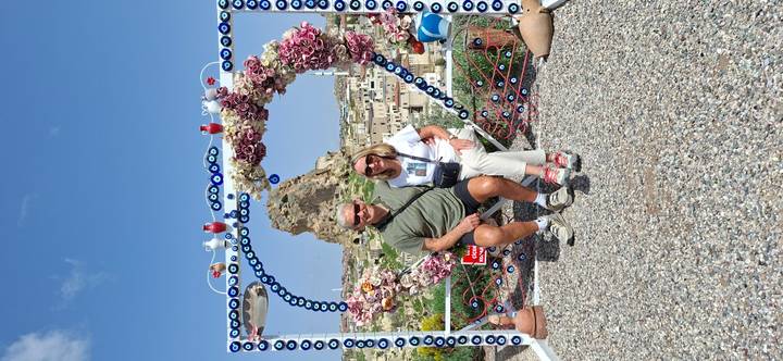 Smiling couple seated in heart-shaped photo frame overlooking Cappadocia town and rock butte