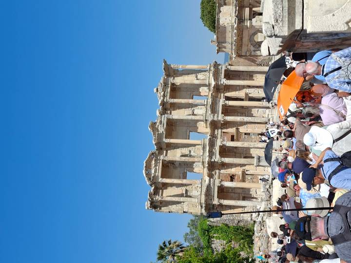 Large crowd entering the ancient Library of Celsus ruins at Ephesus under clear blue sky