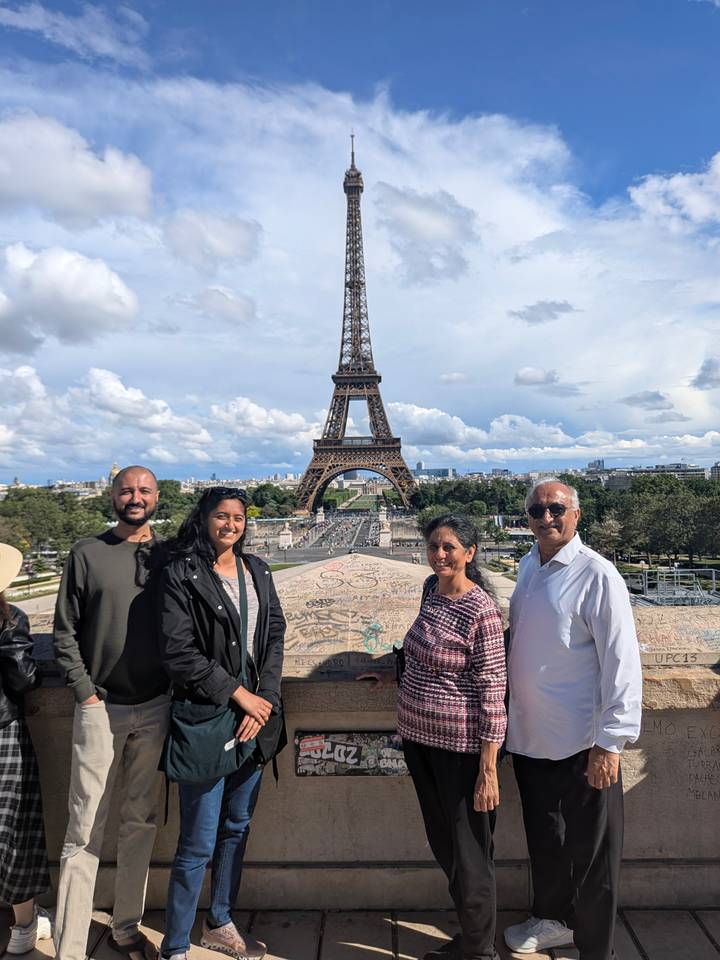 Travellers pose before the Eiffel Tower against a backdrop of dramatic clouds.