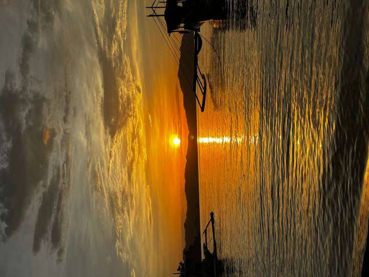 Golden sunset over calm sea with silhouette of traditional outrigger boats.