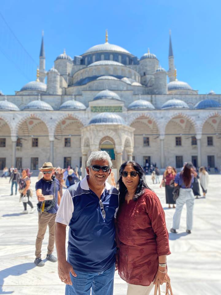 Smiling couple in courtyard of historic mosque with domes and arches under bright sun
