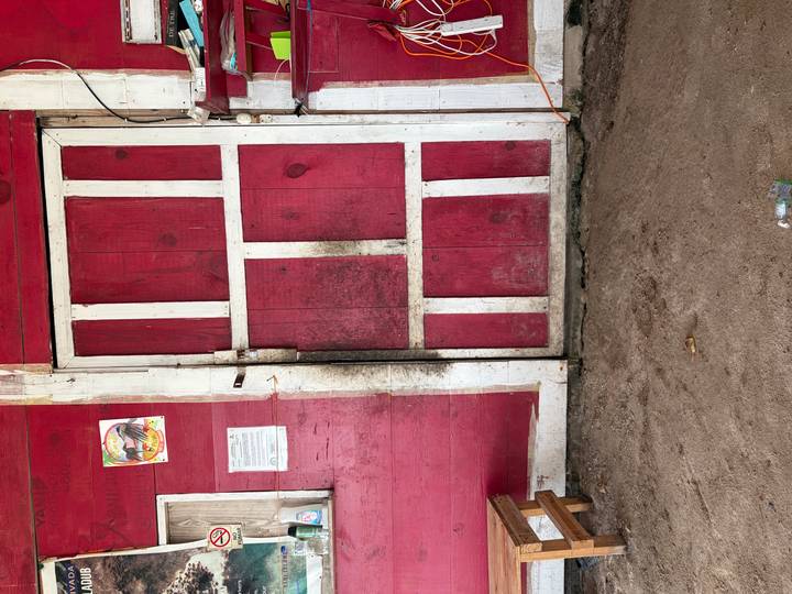 A weather-worn red wooden door with peeling paint and dirt marks