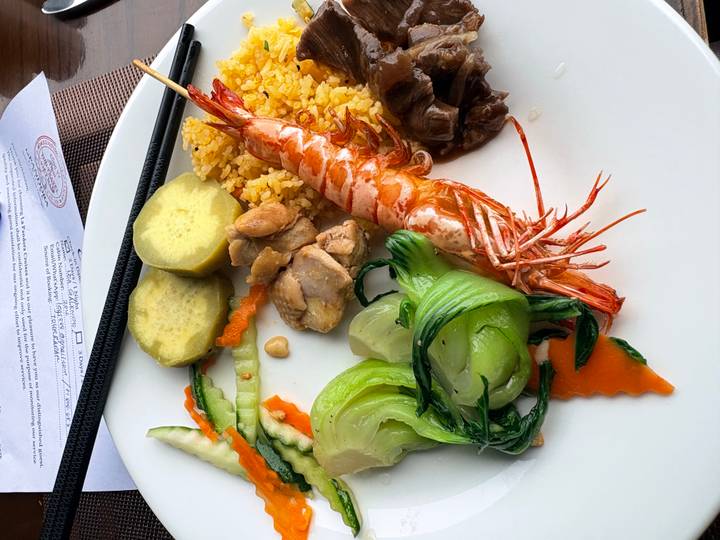 Colourful plate of prawns, chicken, vegetables and rice served on a cruise dining table.