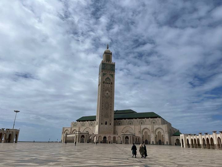 The towering minaret of Hassan II Mosque rises against a partly cloudy sky on Casablanca’s waterfront esplanade.