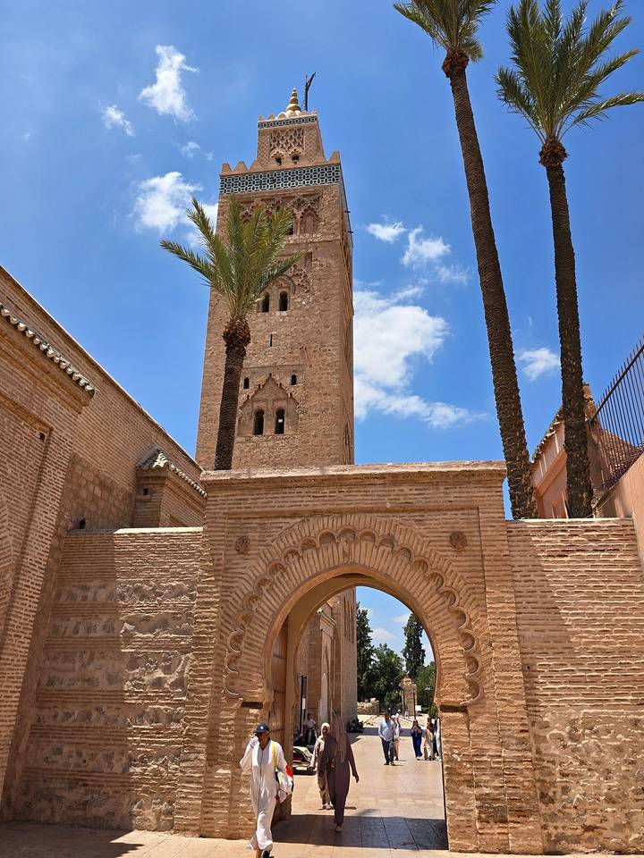The Koutoubia Mosque’s sandstone tower framed by palm trees and a bright blue Marrakesh sky.