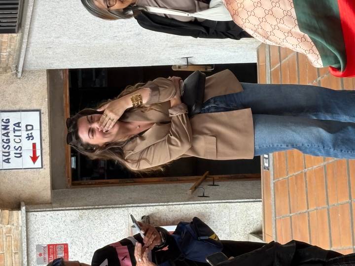 Candid moment of a woman laughing with hand over mouth outside a historic building entrance.