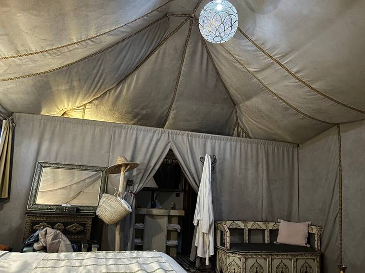 Cozy interior of a canvas desert tent with traditional furnishings and soft lighting.