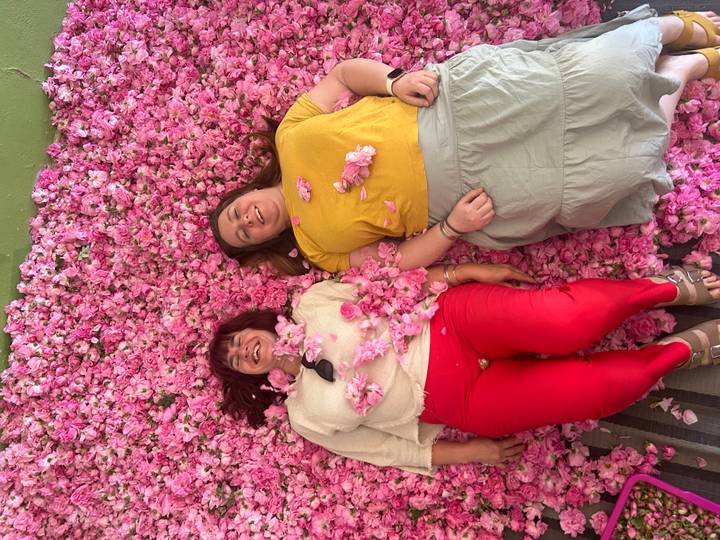 Two women lying amid thousands of fragrant pink rose petals during the Valley of Roses festival.