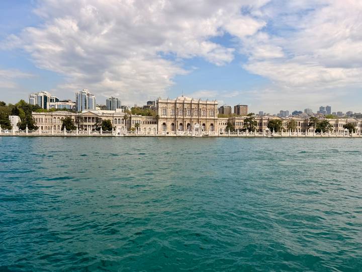 Grand Dolmabahçe Palace façade viewed across the shimmering Bosphorus waters in Istanbul.