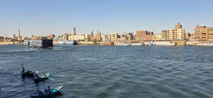 Boats glide along the wide Nile River with Cairo’s skyline of minarets and buildings lining the opposite bank.