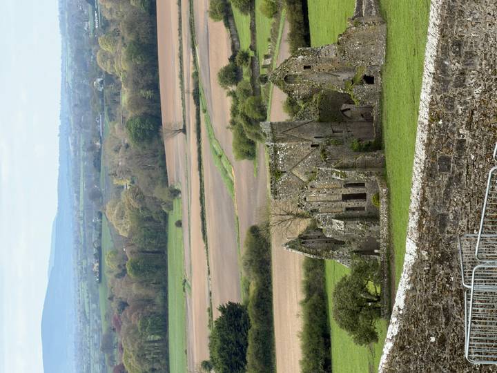Sweeping rural Irish landscape with ruins of medieval abbey amid patchwork fields.