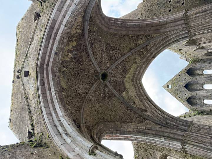 Gothic stone archway interior of a ruined cathedral looking up to the sky.