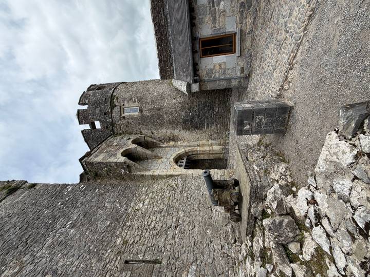 Medieval stone castle courtyard featuring an old cannon and arched entrance.