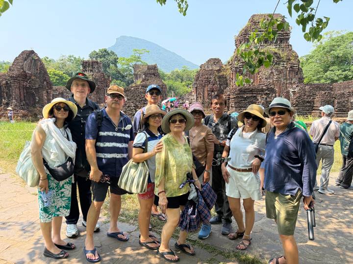 Travellers gather among the red-brick temples and lush greenery of My Son Sanctuary.