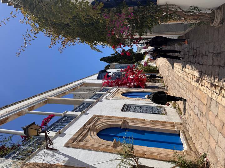 Charming blue-and-white alley in Sidi Bou Said lined with bright bougainvillea and visitors strolling along a cobbled path.