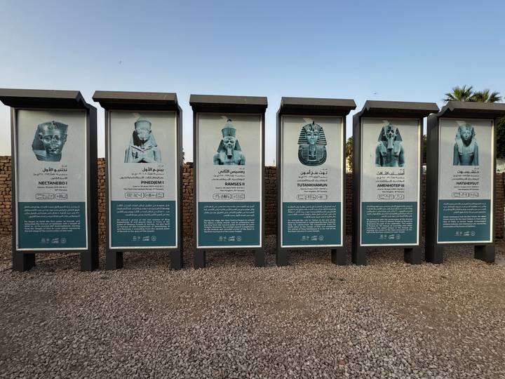 Row of outdoor panels displaying images and descriptions of ancient Egyptian pharaohs in Luxor.