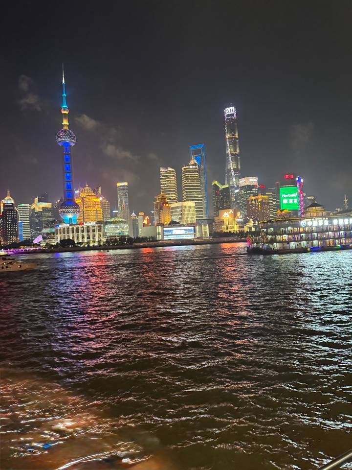 Nighttime panorama of Shanghai’s illuminated Pudong skyline reflecting vibrant colors across the Huangpu River.