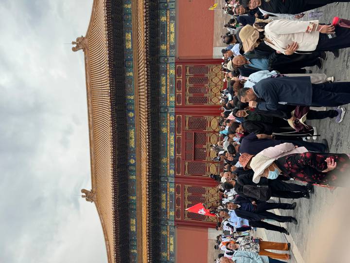 Large crowd of visitors gathered outside a richly ornamented Forbidden City gate.