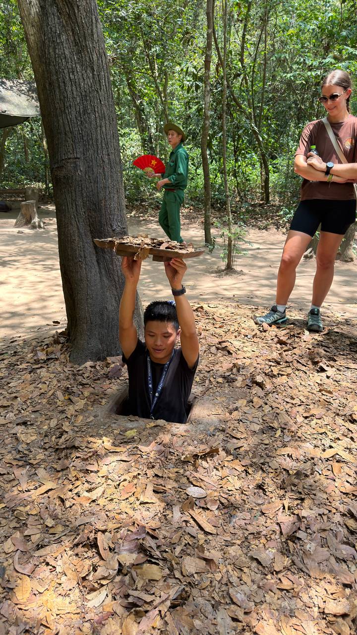 Visitor demonstrates emerging from a narrow tunnel entrance at the historic Cu Chi tunnels.
