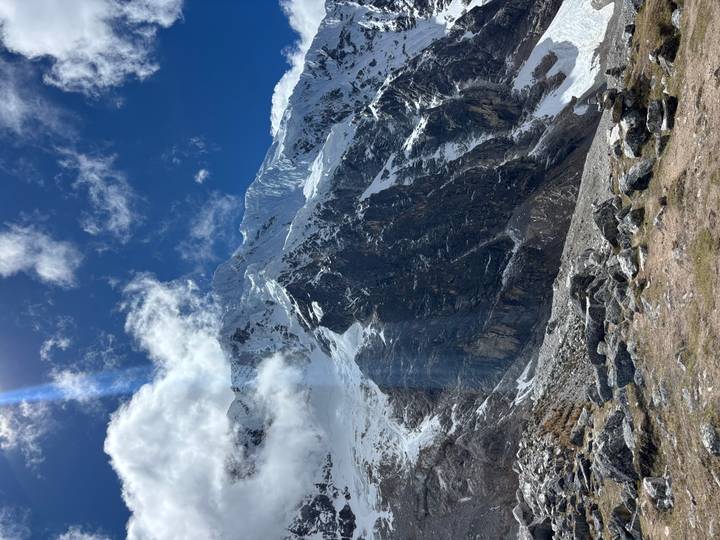 Sunbeam streaks across towering rocky Andes with patches of snow under a deep blue sky