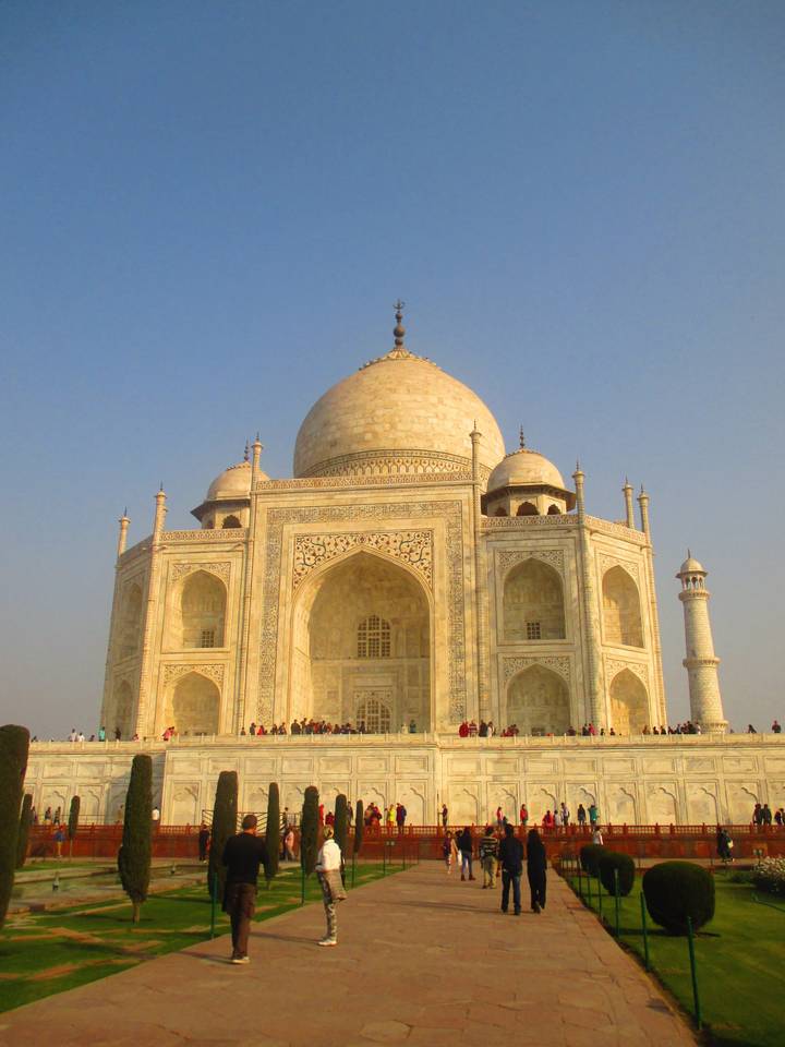 Majestic white marble Taj Mahal with crowds at its base under clear sky