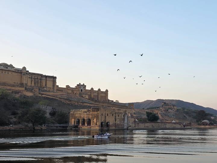 Amber Fort and Maota Lake with birds flying at dawn