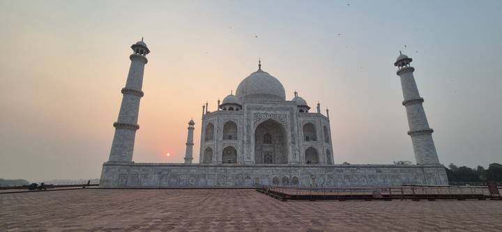 Iconic Taj Mahal with delicate sunrise light and a tiny sun orb beside the minaret.