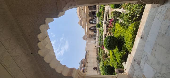 Lush Mughal garden framed by scalloped marble archways and decorative domes.