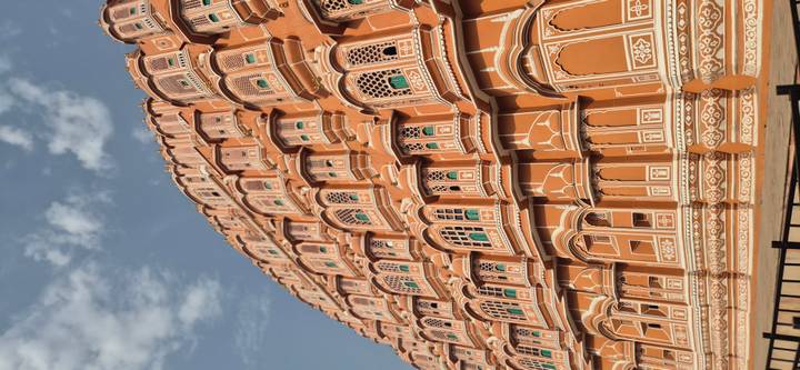 Close-up view of the honeycomb façade and ornate windows of Jaipur's Hawa Mahal under a blue sky.