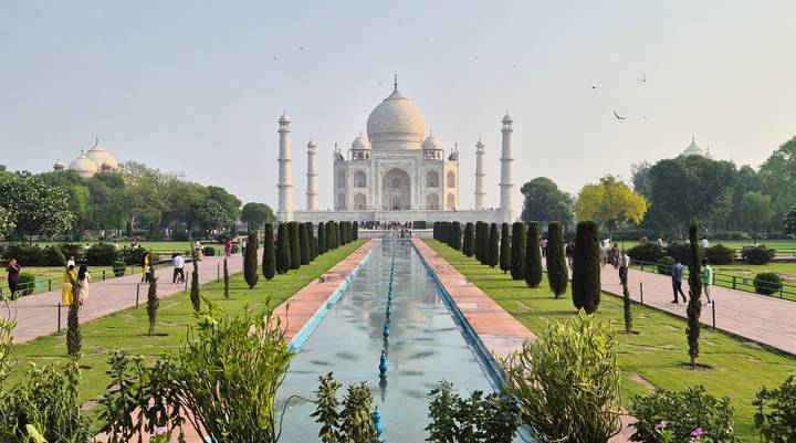 Classic frontal view of the Taj Mahal gardens with reflecting pool and visitors on pathways.