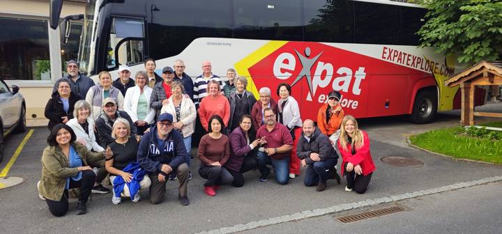 Large tour group posing in front of Expat Explore coach on roadside.