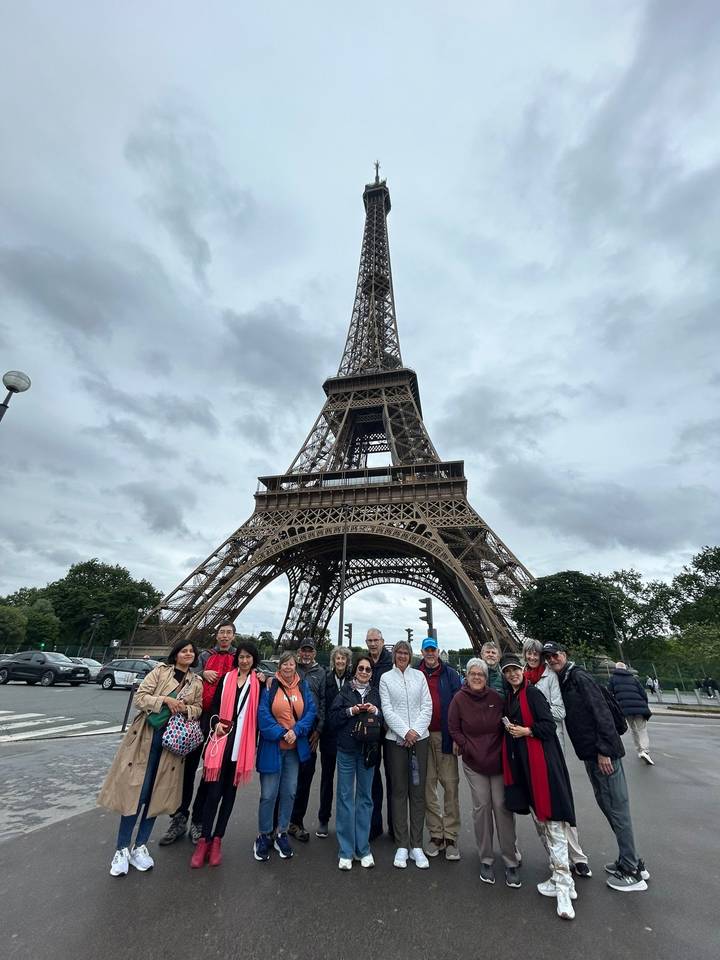 Tour group gathered in front of the Eiffel Tower on an overcast day.